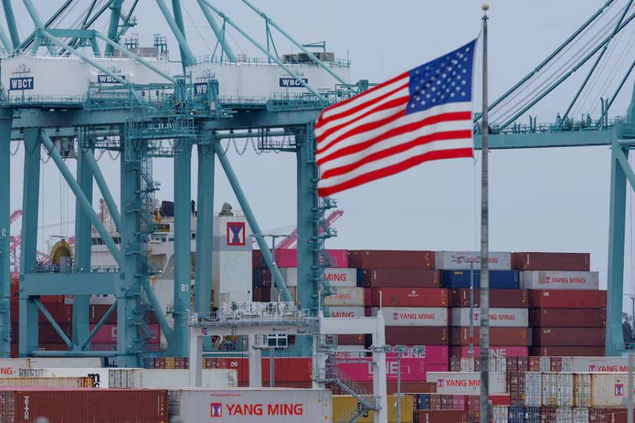A US flag flutters near shipping containers as a ship is unloaded at the Port of Los Angeles, in San Pedro, California, US, May 1, 2025.