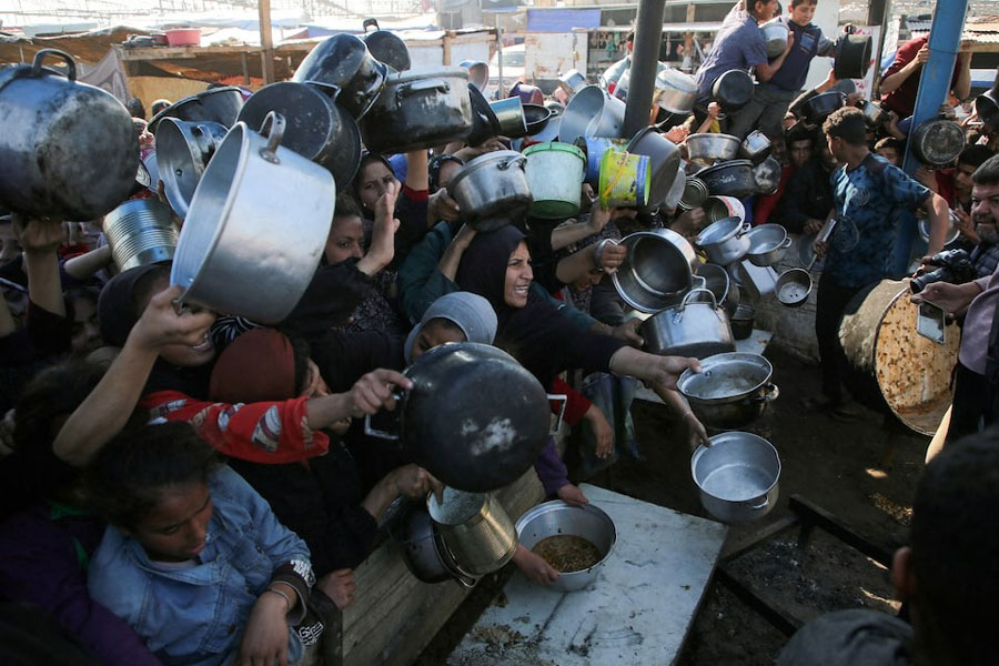 Palestinians gather to receive food cooked by a charity kitchen, amid a hunger crisis, as the Israel-Hamas conflict continues, in Khan Younis in the southern Gaza Strip, January 2, 2025.