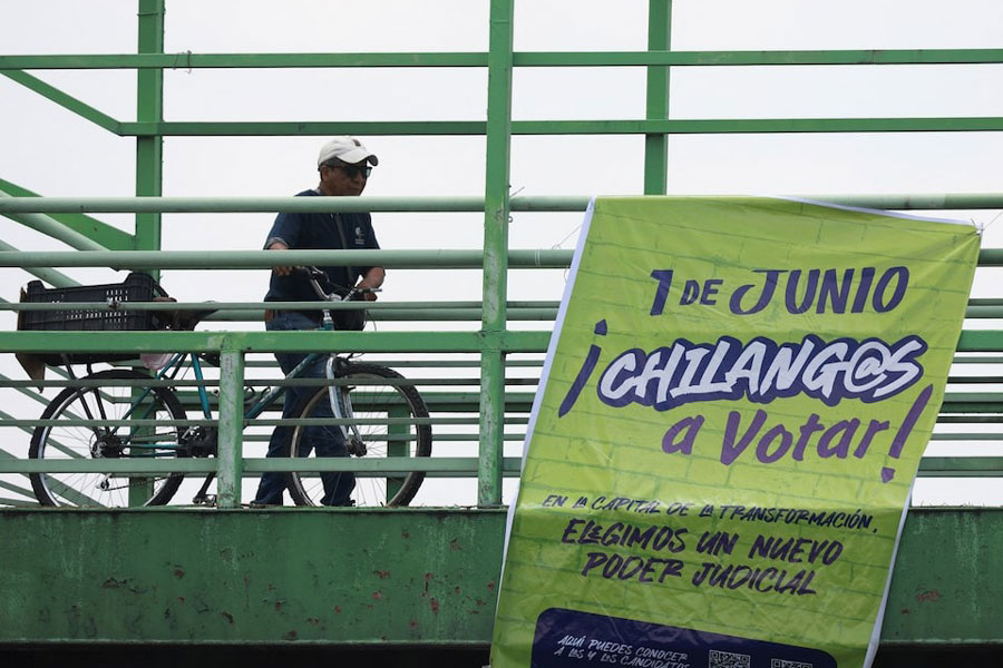 A man pushes his bicycle as an electoral propaganda banner hangs from a pedestrian bridge encouraging people to vote, ahead of the judicial and magistrate election, in Mexico City, Mexico May 29, 2025.