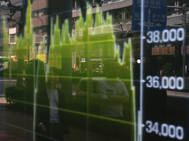Pedestrians are reflected on a stock quotation board showing a graph of Nikkei share average outside a brokerage in Tokyo, Japan April 14, 2025. REUTERS/Kim Kyung-Hoon/File Photo