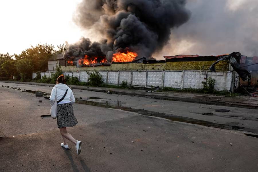 A passerby walks near a building on fire at the site of a Russian drone strike, amid Russia's attack on Ukraine, in Kyiv, Ukraine June 10, 2025.