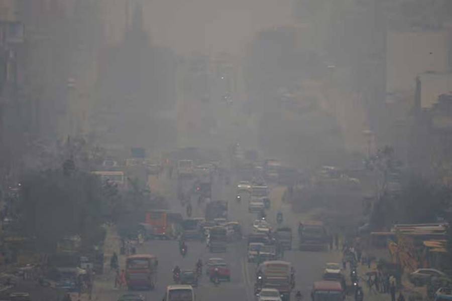 People walk along a road as dust blows into the air, in Dhaka, Bangladesh, June 2, 2025.