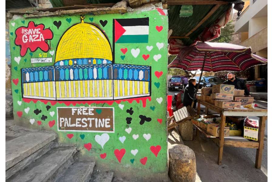 A vendor stands next to a mural in support of Palestinians in Gaza strip amid the ongoing conflict between Israel and the Palestinian Islamist group Hamas, in Cairo, Egypt, November 22, 2023.