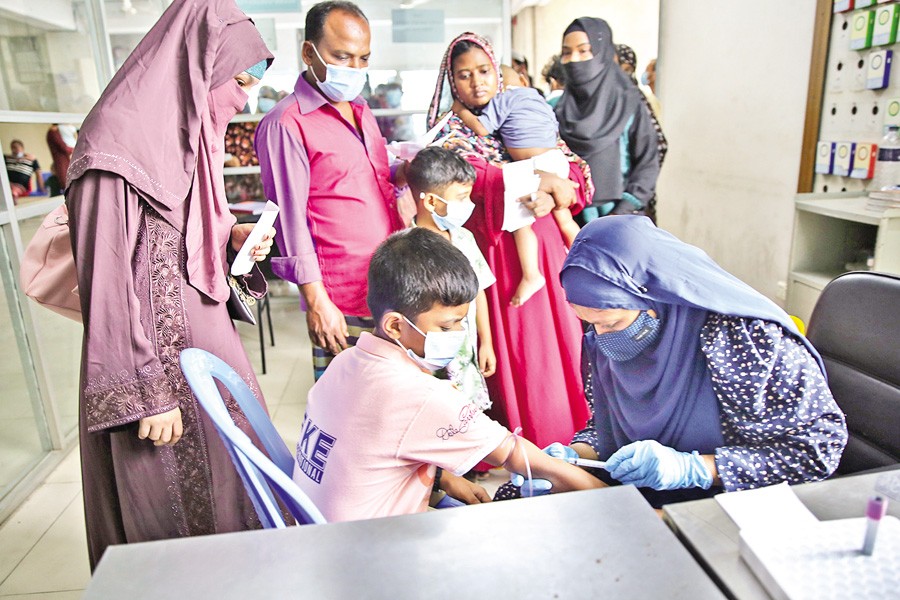 A health worker collects a blood sample from a boy to test for dengue at DNCC Dedicated Covid-19 Hospital in Dhaka's Mohakhali on Saturday. The number of dengue patients, coupled with coronavirus cases, has been rising continuously, which has been a cause for serious concern. — FE Photo by K Asad-Uz-Zaman