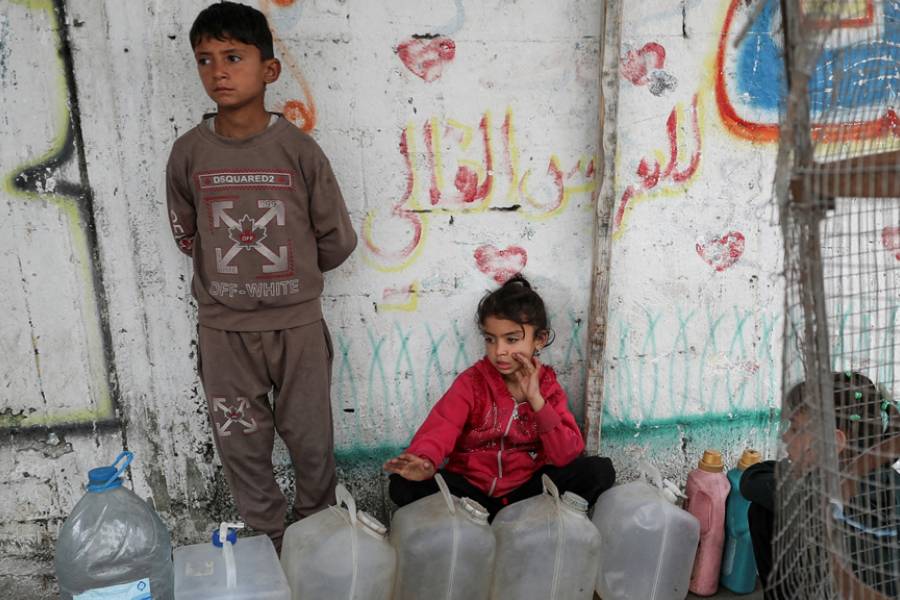 Palestinian children gather near containers used for water, in Gaza City, Apr 6, 2025.