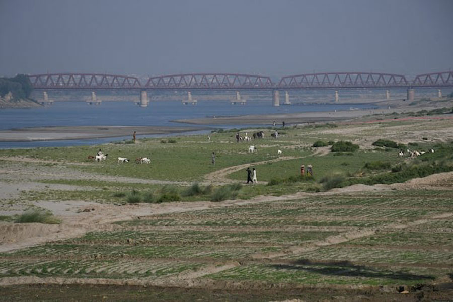 People walk next to a cultivated land on the dry riverbed of the Indus River in Hyderabad, Pakistan April 25, 2025.