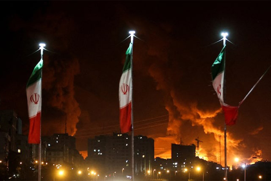Iranian flags fly as fire and smoke from an Israeli attack on Sharan Oil depot rise, following Israeli strikes on Iran, in Tehran, Iran on June 15, 2025 — WANA (West Asia News Agency) via REUTERS/File