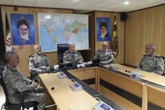In this photo released on Monday, June 23, 2025, by Iranian army press service, Iran's army commander-in-chief Gen. Amir Hatami, center, accompanied by high ranked army commanders, speaks in a video call with top commanders of the army, in Zolfaghar central headquarters, Iran, as portraits of the late revolutionary founder Ayatollah Khomeini, left, and Supreme Leader Ayatollah Ali Khamenei hang on the wall. (Iranian Army Press Service via AP)