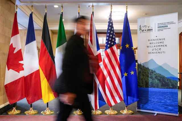 A man walk past the G7 members flags at the Manoir Richelieu before the G7 Foreign Ministers summit in La Malbaie, Quebec, Canada March 12, 2025.