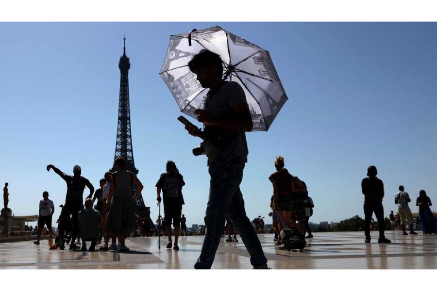A tourist holding an umbrella to protect himself from the sun walks at Trocadero square next to the Eiffel Tower as an early summer heatwave hits Paris, France, Jul 1, 2025.