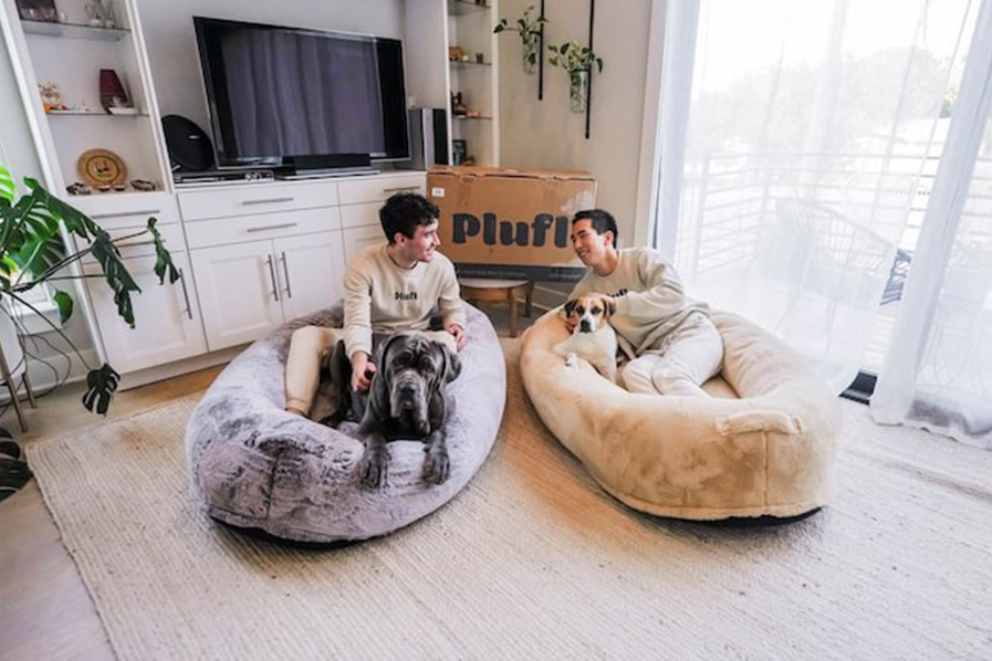 Plufl founders Noah Silverman and Yuki Kinoshita pose with their China-made "human dog bed" in a store, in this undated handout photo at an unspecified location — Handout via REUTERS