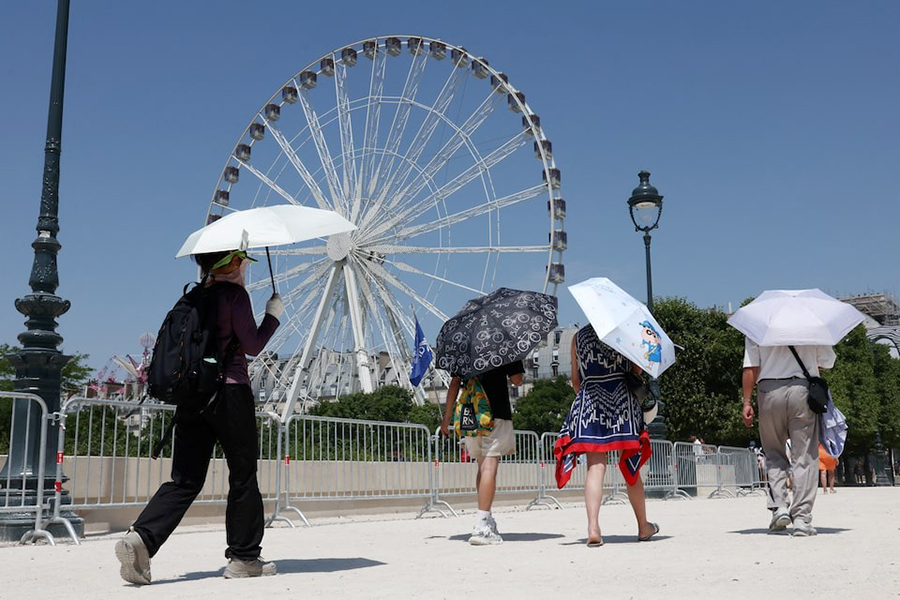 Tourists, holding an umbrella to protect themselves from the sun, walk past a Ferris wheel in the Tuileries Garden on a sunny and warm summer day in Paris as an early summer heatwave hits France on July 2, 2025 — Reuters photo