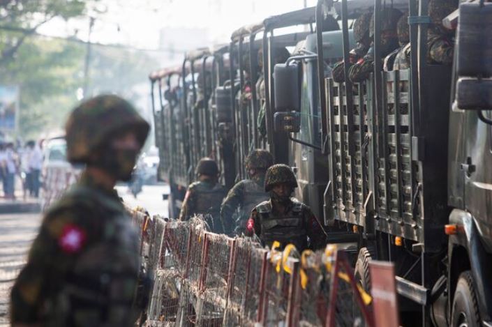 Soldiers stand next to military vehicles as people gather to protest against the military coup, in Yangon, Myanmar, February 15, 2021. REUTERS/Stringer/File Photo