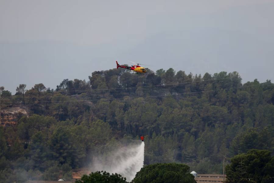A helicopter helps to extinguish an ongoing wildfire in Xerta, which is one of the confined villages in the Tarrragona province in Catalonia, Spain, July 8, 2025.
