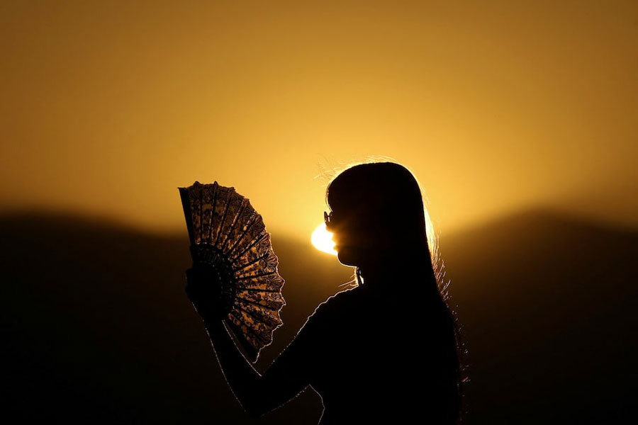 A girl cools off from the heat with a paper fan in Skopje, North Macedonia, July 3, 2025.