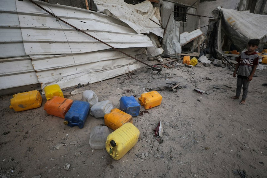 A Palestinian boy inspects the site of an Israeli strike that killed Palestinians, gathered to collect water from a distribution point, according to medics, in Nuseirat in the central Gaza Strip July 13, 2025.