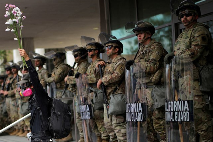 A demonstrator raises his hand holding flowers as members of the National Guard stand in formation outside a federal building during the No Kings protest against US President Donald Trump's policies, in Los Angeles, California, US on June 14, 2025 — Reuters photo