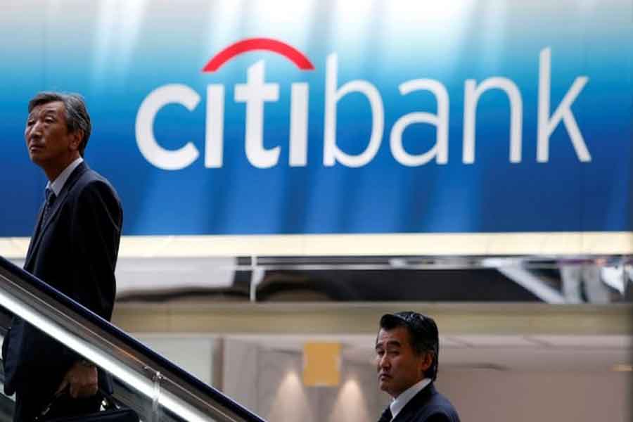 Men travel on an escalator near a Citibank signboard in Tokyo June 26, 2009.