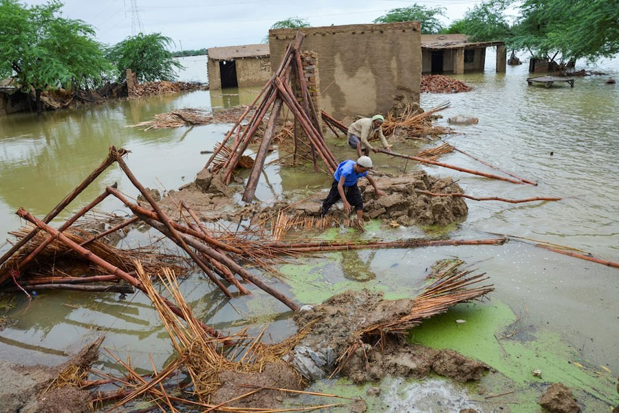 People retrieve bamboos from a damaged house following rains and floods during the monsoon season in Dera Allah Yar, district Jafferabad, Balochistan, Pakistan August 25, 2022.