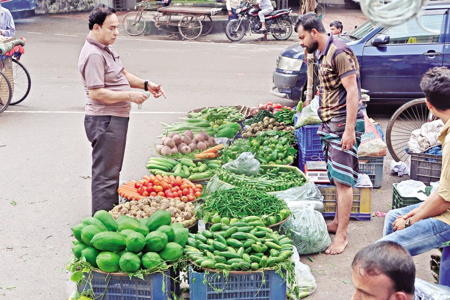 A buyer asking for prices of vegetables at a footpath shop in the capital's Dilkusha area on Thursday. — FE Photo