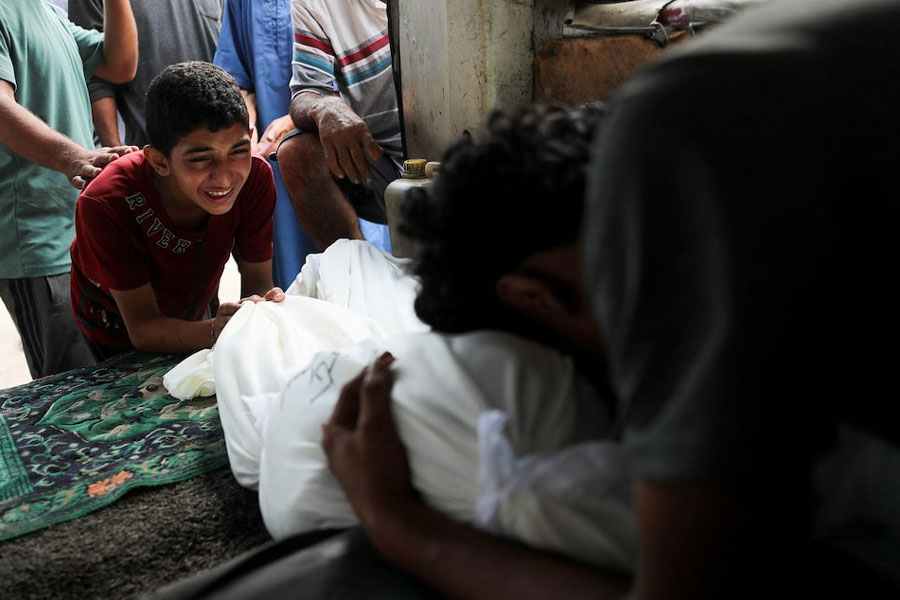 Mourners react next to a body during the funeral of Palestinians killed in an early morning Israeli strike, according to medics, at Al-Shifa Hospital in Gaza City, July 19, 2025.