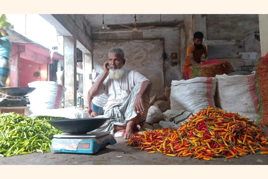 Traders with a display of green chilli for sale at a shop in Bogura town. The key cooking ingredient has become prohibitive in the district and elsewhere across the country in recent time