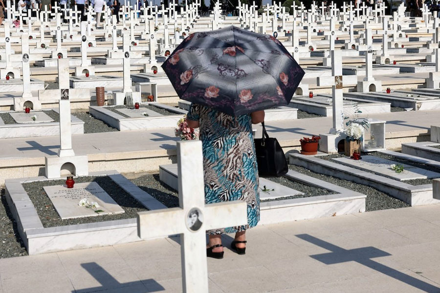 A woman walks next to the graves of soldiers killed in the 1974 Turkish invasion of Cyprus at the Tymvos Makedonitissas military cemetery in Nicosia, Cyprus July 20, 2025. REUTERS/Yiannis Kourtoglou