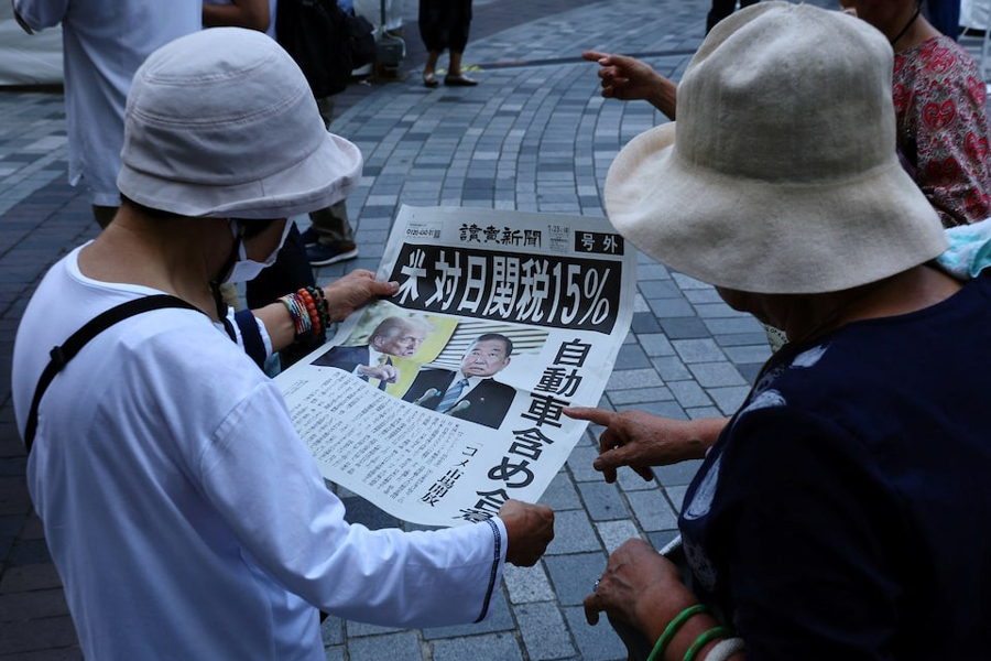 People react as they read a special edition of Yomiuri Shimbun newspaper reporting the tariff deal agreement between US and Japan, in Tokyo, Japan, July 23, 2025.