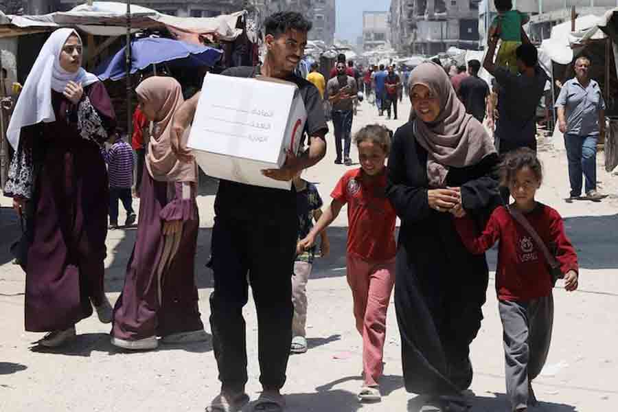 The son of displaced Palestinian woman Iman Suleiman, from Beit Lahiya, carries a box of aid the family received, distributed by the Emirates Red Crescent, in Gaza City, June 26, 2025.