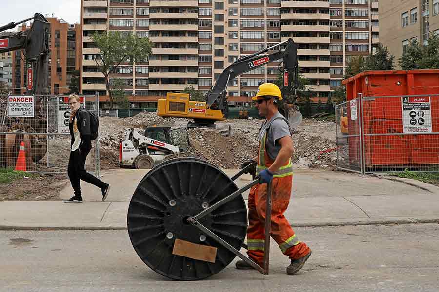 A construction worker passing a condominium site with a roll of cable in Toronto of Canada –Reuters file photo