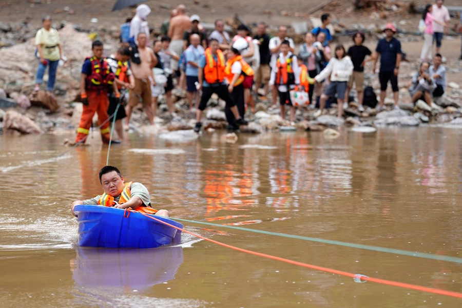 A man sits in a plastic boat to move to safety after heavy rainfall flooded the region, in Huairou district of Beijing, China on July 28, 2025 — cnsphoto via REUTERS