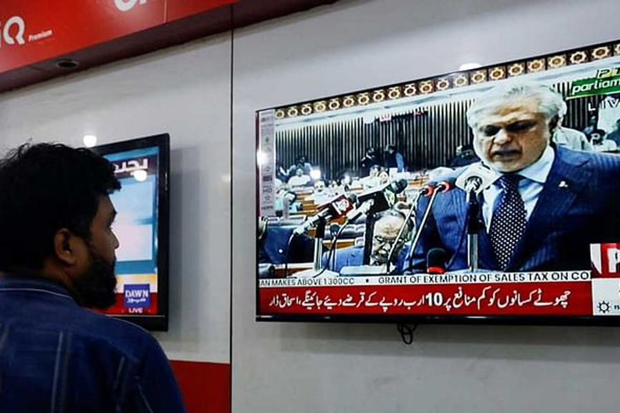 A salesman looks at a television screen showing Pakistan's Finance Minister Ishaq Dar presenting the budget for the 2023/24 fiscal year in the parliament in Islamabad, at a shop in Karachi, Pakistan, Jun 9, 2023.