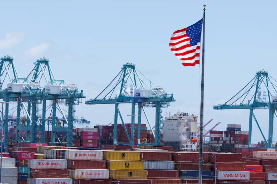 An American flag flutters over a ship and shipping containers at the Port of Los Angeles, in San Pedro California, U.S., May 13, 2025.