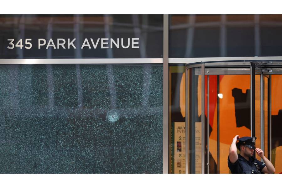 A police officer stands next to the glass window with a bullet hole near the scene of a deadly mass shooting in Manhattan, New York City, US Jul 29, 2025.