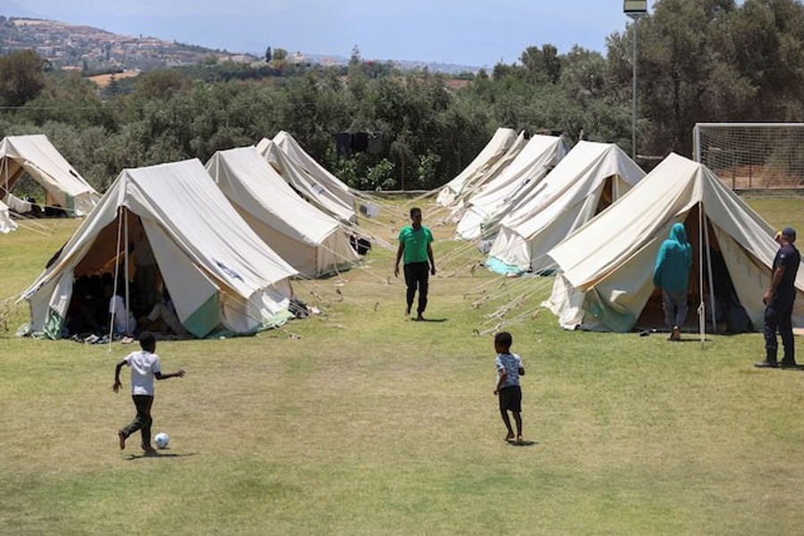 Children play near tents as recently arrived migrants shelter at a temporary camp set up on a soccer pitch in the region of Rethymno on Crete island, Greece, June 24, 2025.
