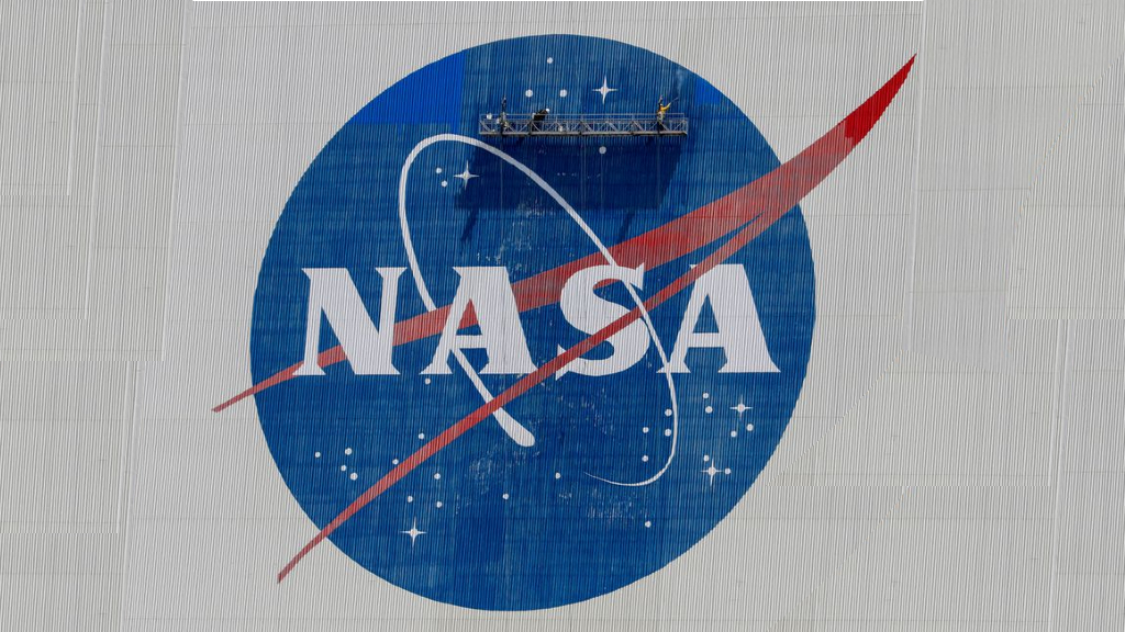 Workers pressure wash the logo of NASA on the Vehicle Assembly Building before SpaceX will send two NASA astronauts to the International Space Station aboard its Falcon 9 rocket, at the Kennedy Space Center in Cape Canaveral, Florida, US, May 19, 2020. REUTERS