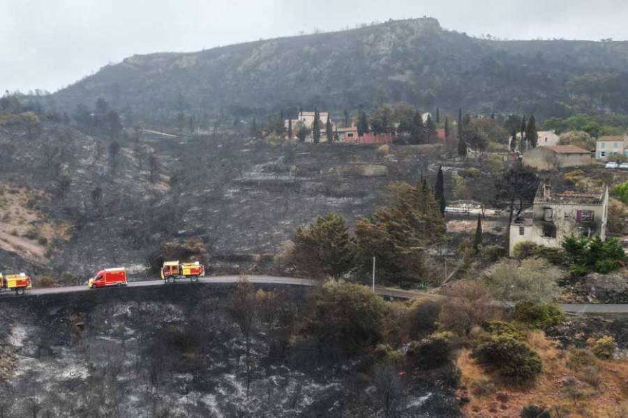 A drone view shows fire trucks driving past a house severely damaged by fire in Jonquieres, near Narbonne, southern France, as wildfires sweep through the region, Aug 8, 2025.