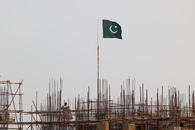 A Pakistani flag flutters over iron scaffoldings as a labourer works at a construction site on the eve of Pakistan's Independence Day celebrations, in Lahore, Pakistan August 13, 2025.