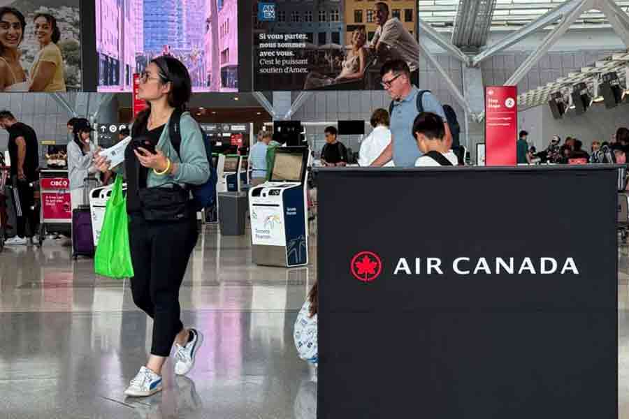 Passengers walk past an Air Canada sign, ahead of a potential strike by flight attendants of the airline, at the Toronto Pearson International Airport in Mississauga, Ontario, Canada, Aug 14, 2025.