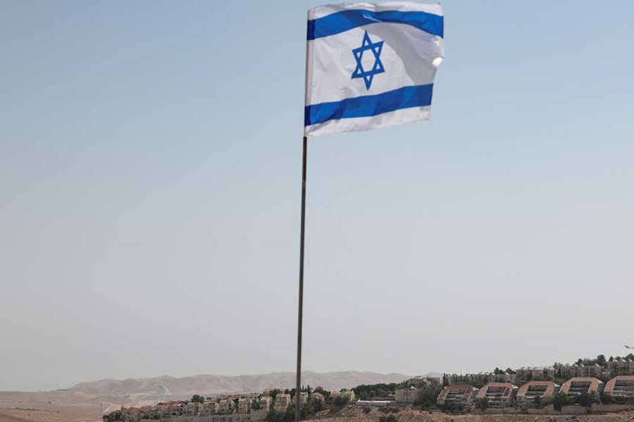An Israeli flag flutters, as part of the Israeli settlement of Maale Adumim is visible in the background, in the Israeli-occupied West Bank, Aug 14, 2025.