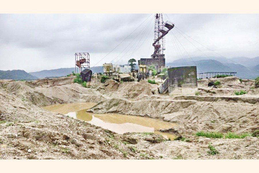 Huge ditches, created by long-term stone looting, are seen at the Bholaganj Ropeway area near the Sadapathar site in Sylhet, with some railway towers and equipment in view. The photo was taken recently. — FE Photo