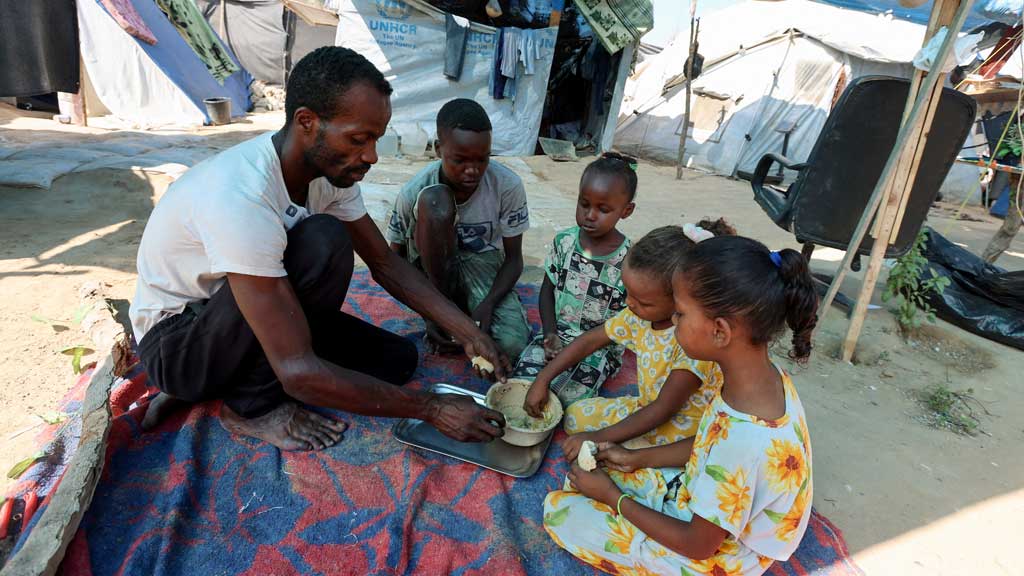 Displaced Palestinian man Tayseer Obaid, who lives in a tent with his wife and eight children and has documented his struggle to obtain food and aid amid a hunger crisis, eats with his children outside their tent, in Deir al-Balah in the central Gaza Strip, August 7, 2025. REUTERS