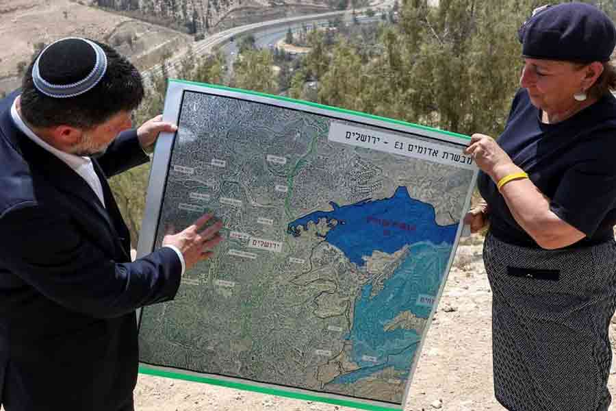 Israeli Finance Minister Bezalel Smotrich and a woman hold a map that shows the long-frozen E1 settlement scheme, that would split East Jerusalem from the occupied West Bank, on the day of a press conference near the Israeli settlement of Maale Adumim, in the Israeli-occupied West Bank, Aug 14, 2025.