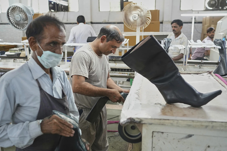 A worker inspects high ankle leather boots before packing in a leather footwear manufacturing unit at Dawar industry in Agra, India on Monday, August 25, 2025 — AP photo