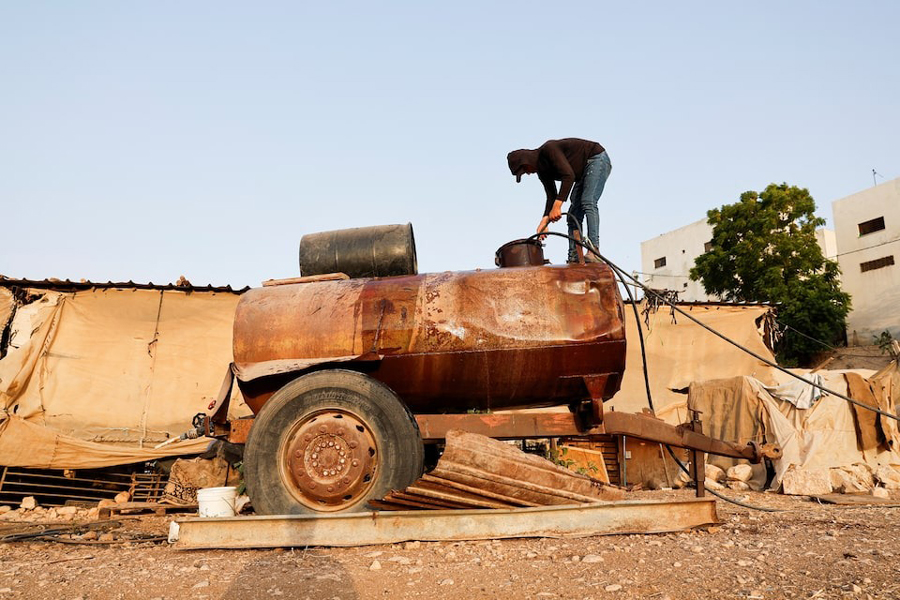 A Palestinian man fills a water tank in Bardala, in Jordan Valley, in the Israeli-occupied West Bank August 13, 2025.