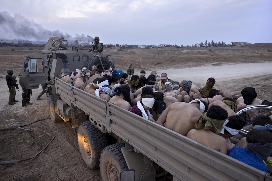 Israeli soldiers stand by a truck packed with bound and blindfolded Palestinian detainees, in Gaza, December 8, 2023 — AP/File
