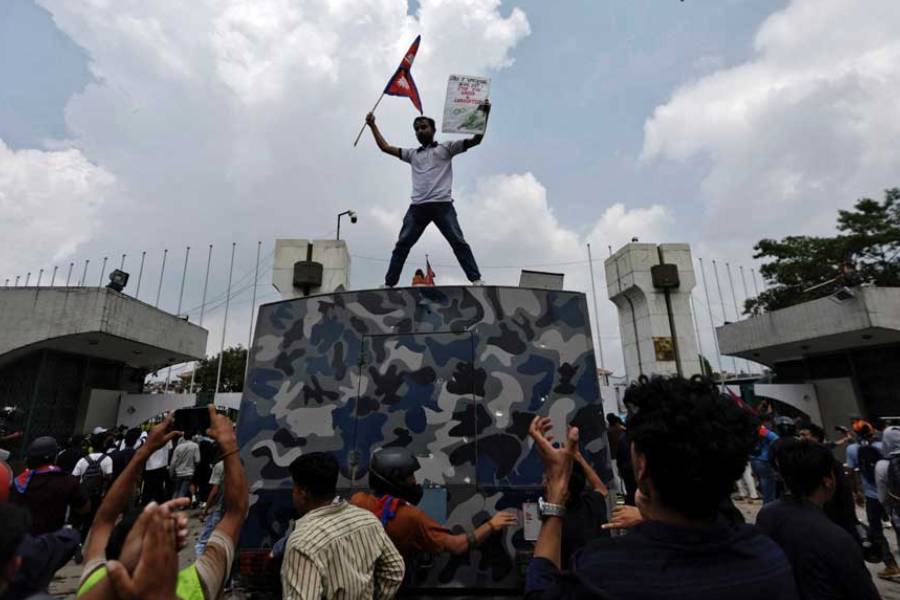 A demonstrator waves a flag as he stands atop a vehicle near the entrance of the Parliament during a protest against corruption and government’s decision to block several social media platforms, in Kathmandu, Nepal September 8, 2025.
