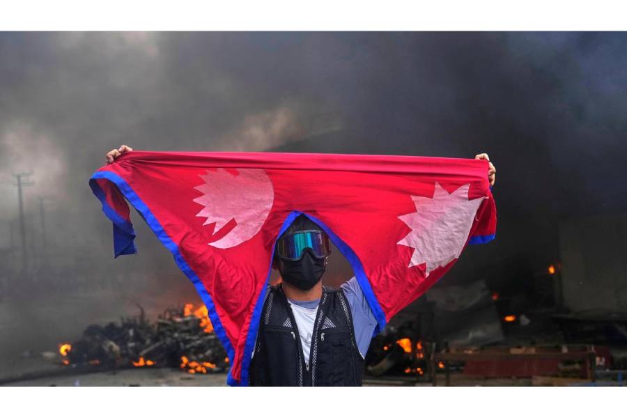A protester shouts slogans carrying national flag after burning down a police station during protests against social media ban and corruption in Kathmandu, Nepal, Tuesday, Sept. 9, 2025.