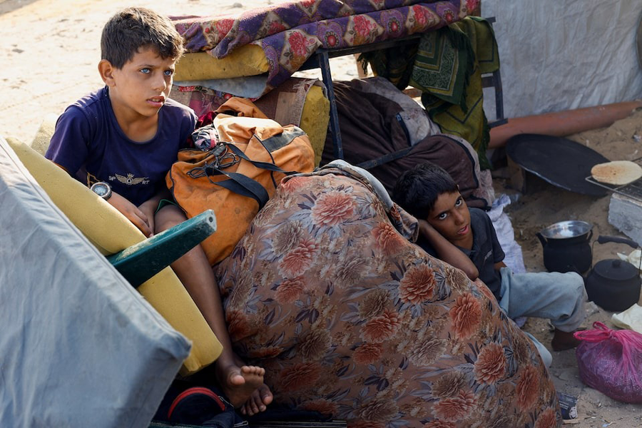 Palestinian boys, who fled northern Gaza after Israeli forces ordered residents of Gaza City to evacuate to the south amid an Israeli military operation, rest at their makeshift shelter, in the central Gaza Strip, September 27, 2025.