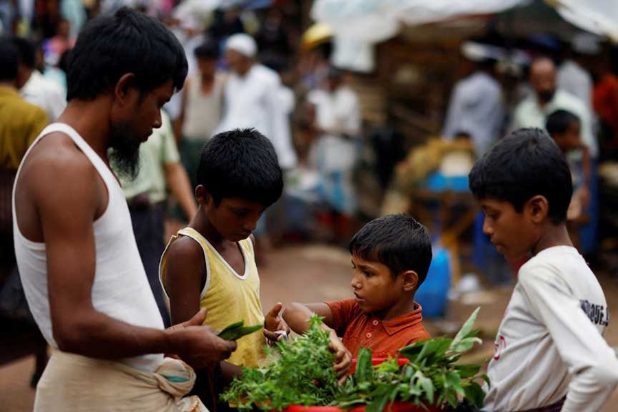 A Rohingya refugee child sells vegetables on the street, along a kitchen market inside a refugee camp, in Cox's Bazar, Bangladesh, Aug 27, 2025.